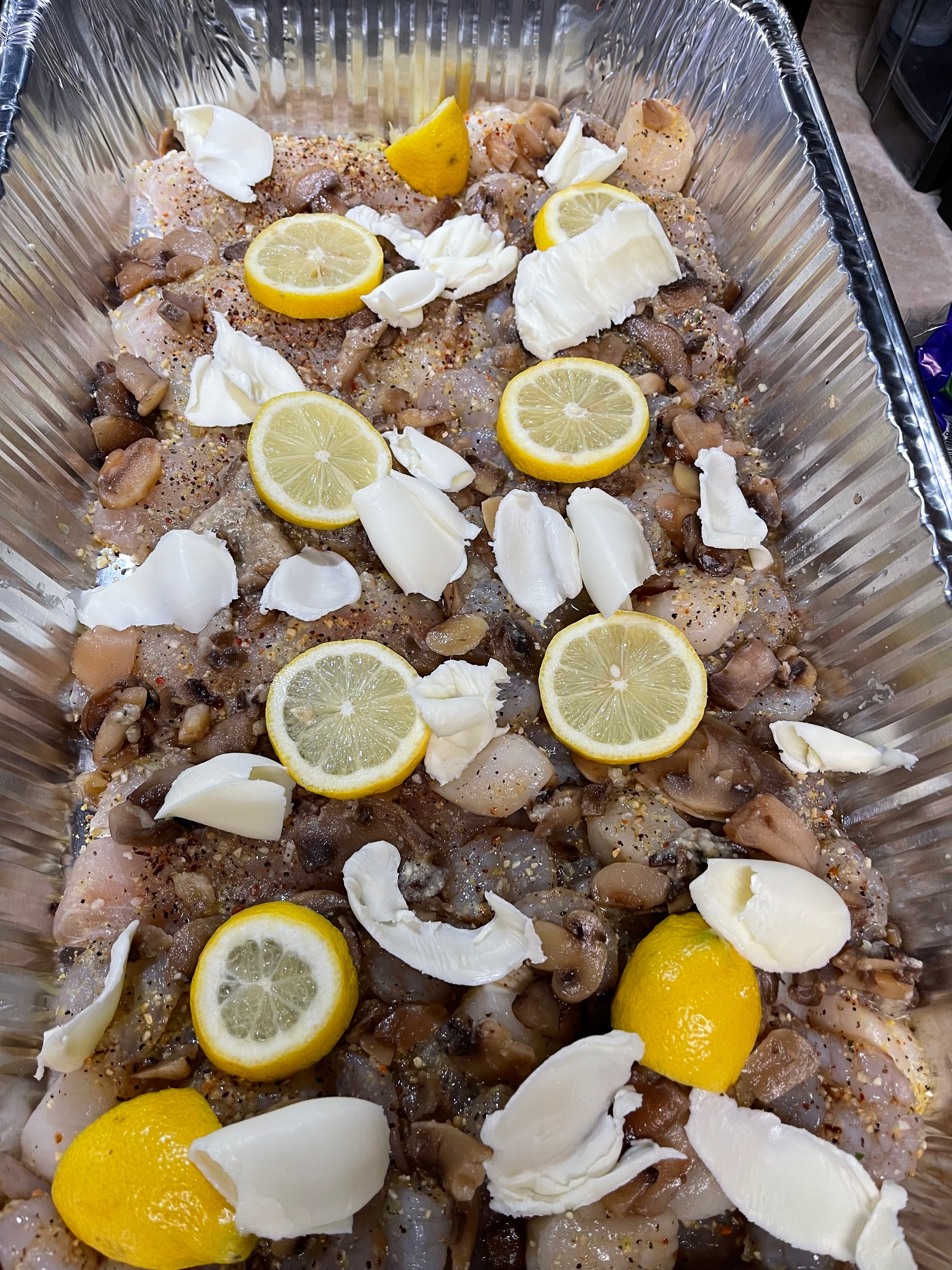 Chicken with lemon slices, butter and mushrooms ready to bake